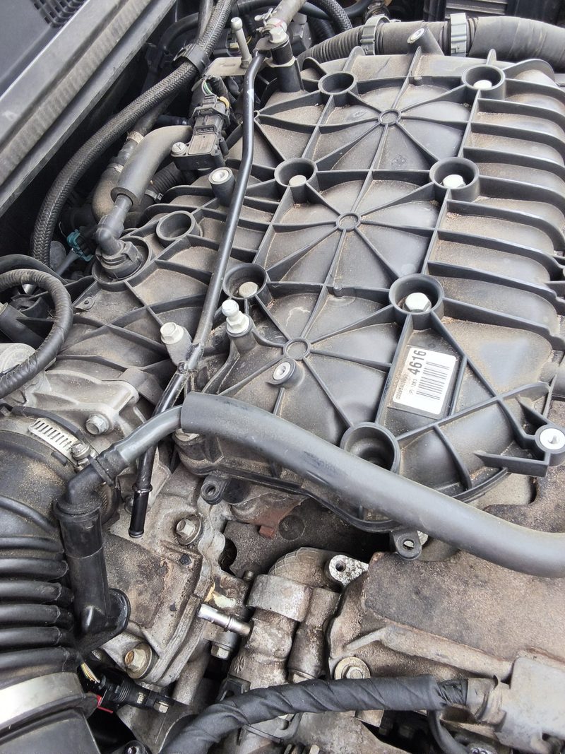 The top of the Buick LaCrosse V6 engine with the intake cover and hoses in view