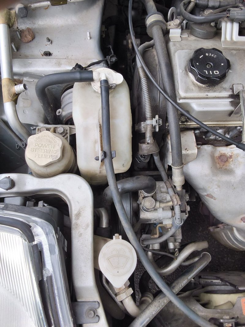 The engine bay of the 2002 Mitsubishi Eclipse with the hood up, reservoirs and hoses in view
