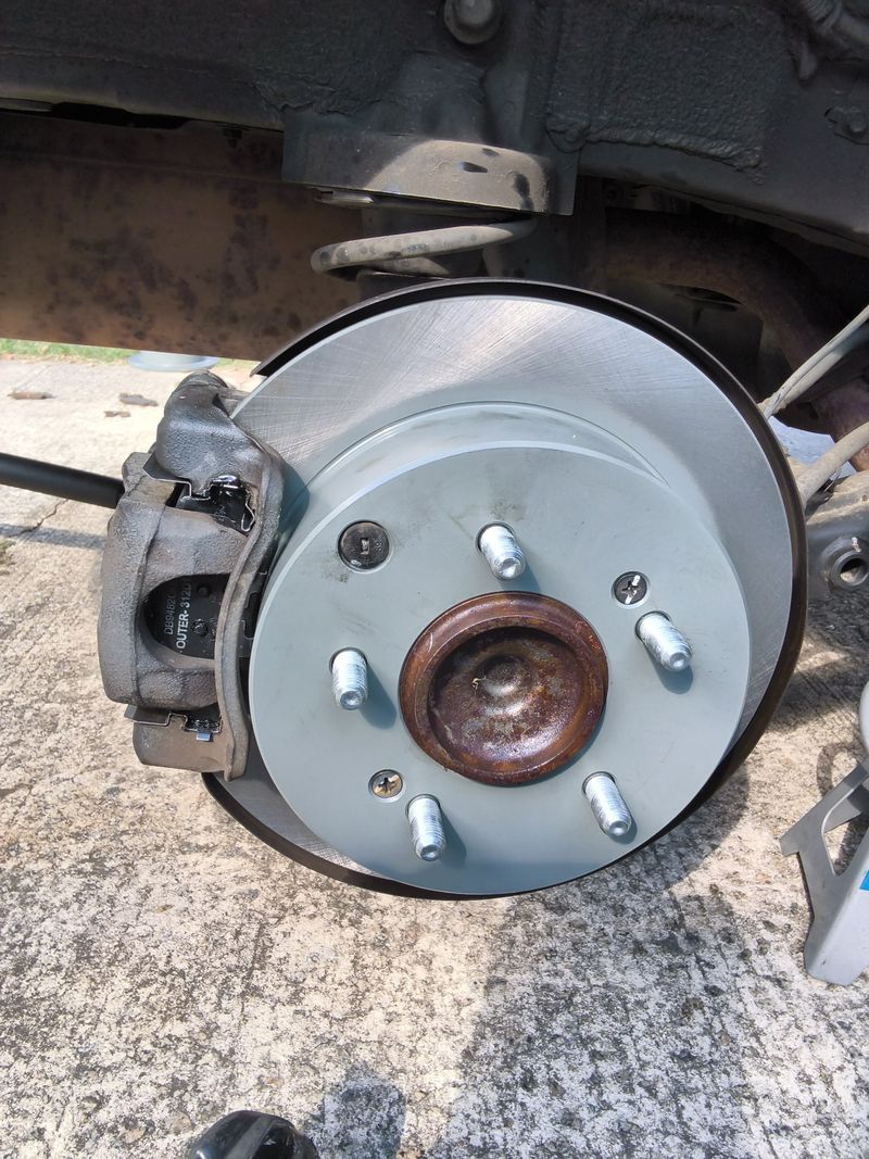 New brake rotor and caliper fitted to a Kia before the wheel goes back on