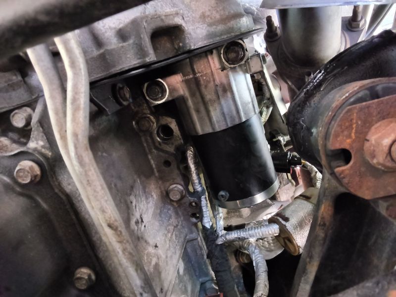 A replacement starter motor bolted in under a Chevy Tahoe in a driveway in Monroe NC