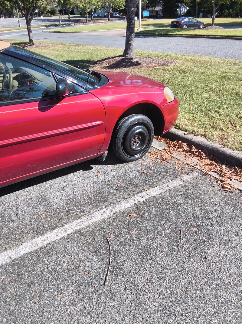 The red Sebring sitting level on its black spare wheel in a parking space
